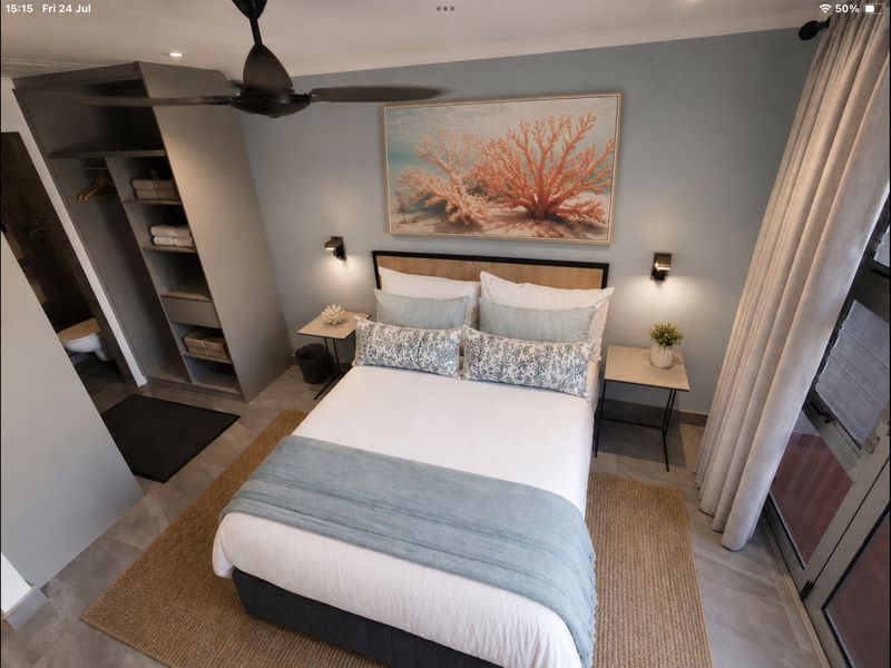 A modern, well-maintained bedroom featuring a built-in wardrobe, ceiling fan, and direct access to an outdoor area through sliding glass doors.