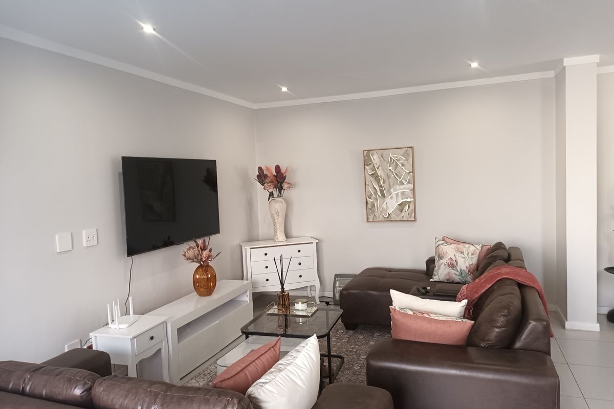 A well-maintained living room featuring neutral wall tones, recessed downlighting, and tiled flooring, providing a clean and comfortable space for relaxation.