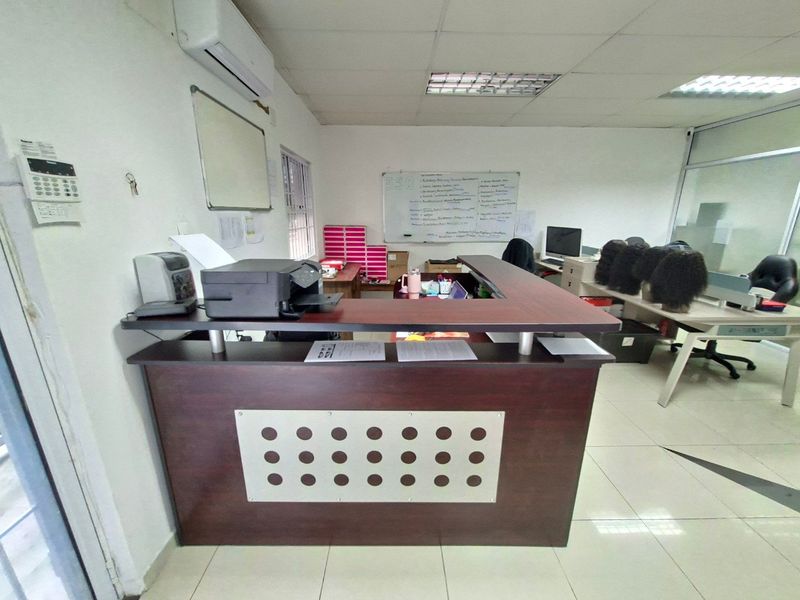 Commercial office space featuring a built-in reception desk, tiled flooring, and a wall-mounted air conditioning unit.