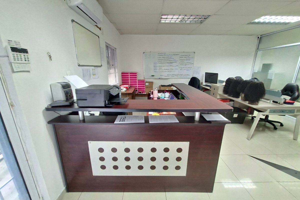 Commercial office space featuring a built-in reception desk, tiled flooring, and a wall-mounted air conditioning unit.
