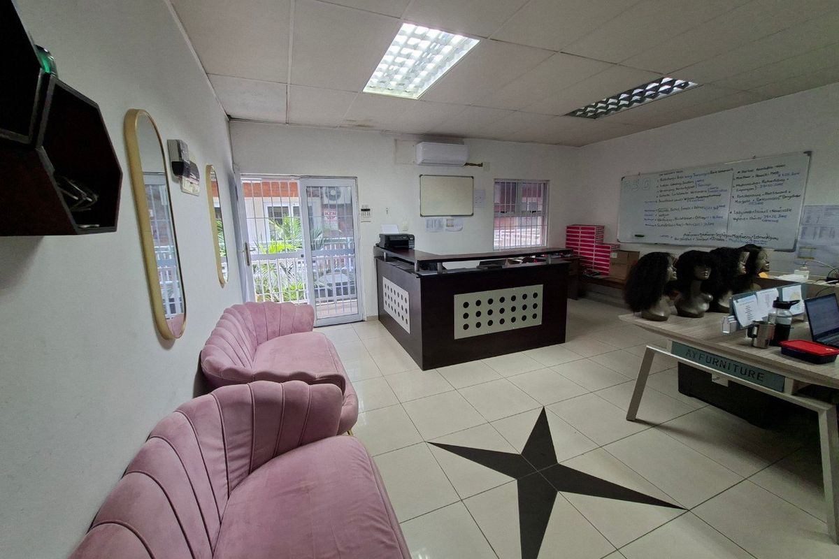 Commercial office space featuring a reception desk, tiled flooring, drop ceiling with integrated lighting, and a wall-mounted air conditioning unit.