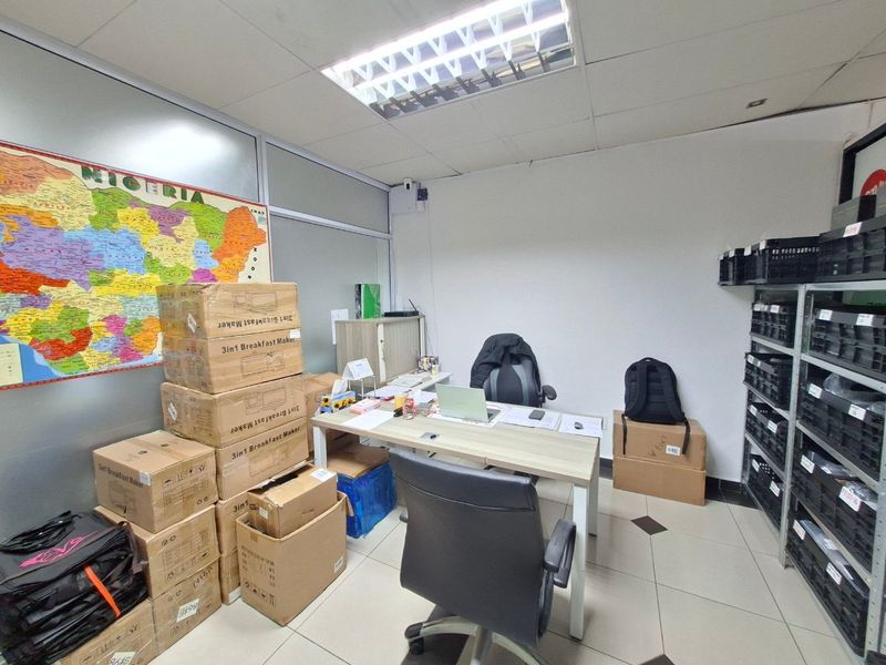 A functional commercial office space featuring tiled flooring, a glass partition wall, and overhead fluorescent lighting.