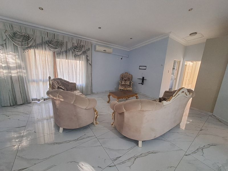 Spacious living room featuring polished marble-look floor tiles, recessed downlighting, and a wall-mounted split-system air conditioner.