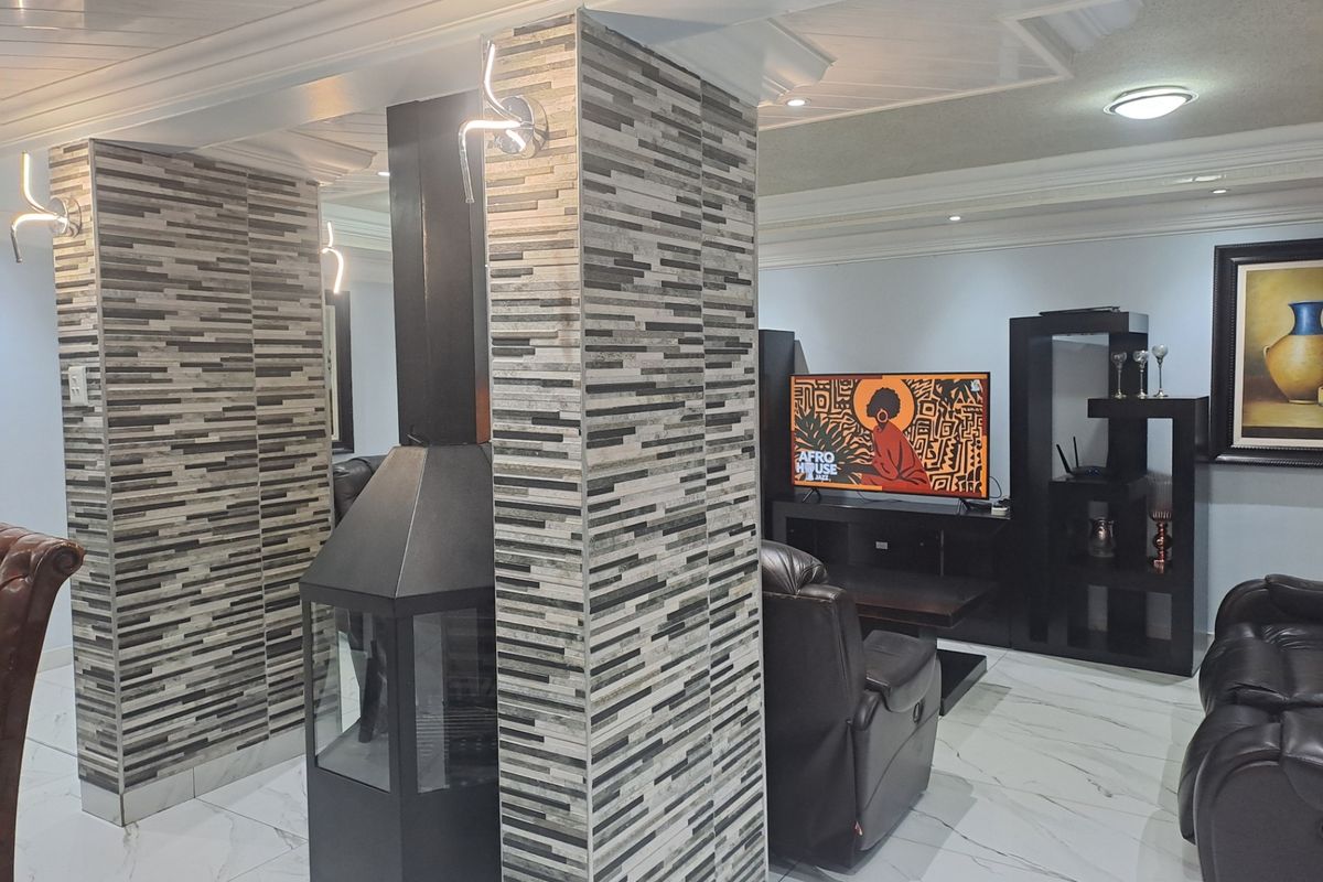 Spacious living area featuring a modern freestanding fireplace, decorative tiled columns, recessed ceiling lighting, and polished marble-look floor tiles.