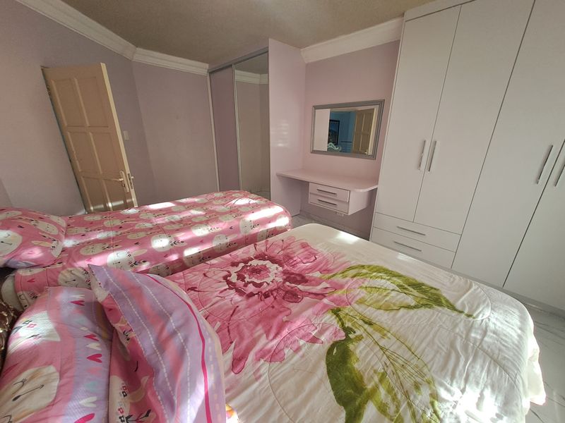 A bedroom featuring built-in cupboards, a vanity unit, coved ceilings, and tiled flooring.