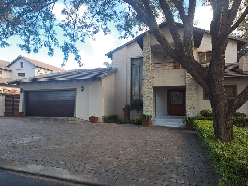A well-maintained double-story residence featuring a paved driveway, double garage, stone-clad accents, and a covered entrance with a balcony.