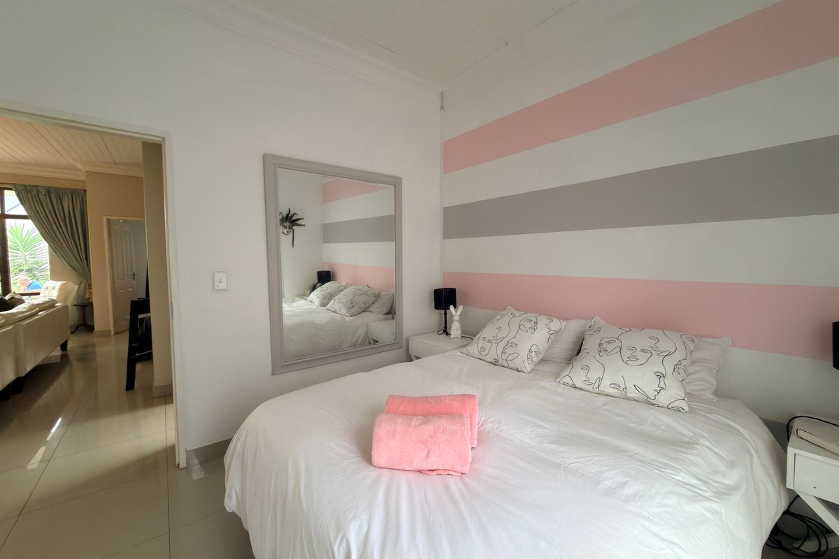 A well-maintained bedroom featuring tiled flooring, a tongue and groove ceiling, and a decorative striped accent wall.