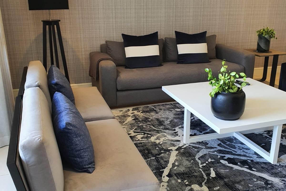 A well-maintained living room featuring neutral textured wallpaper and clean tiled flooring, creating a comfortable and modern atmosphere.