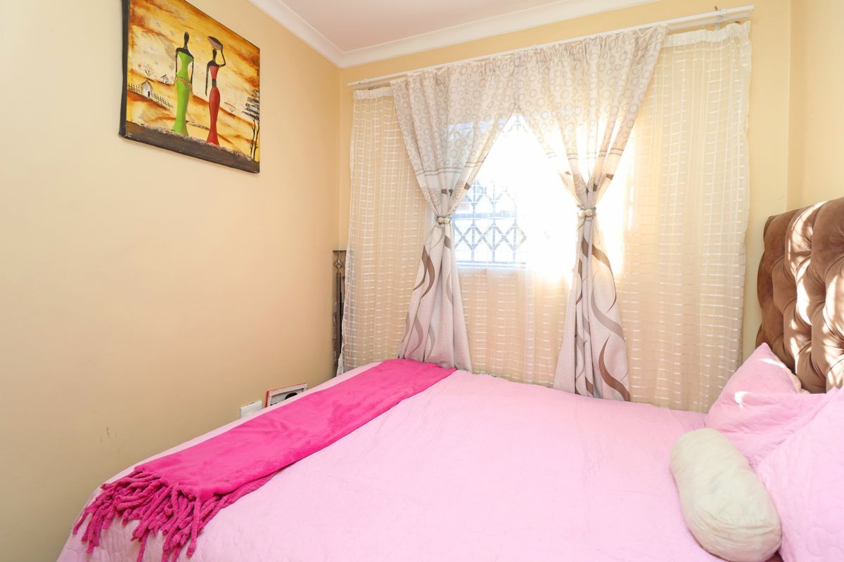 A cozy bedroom featuring a window with security gate and decorative cove cornicing, providing a functional and comfortable sleeping space.
