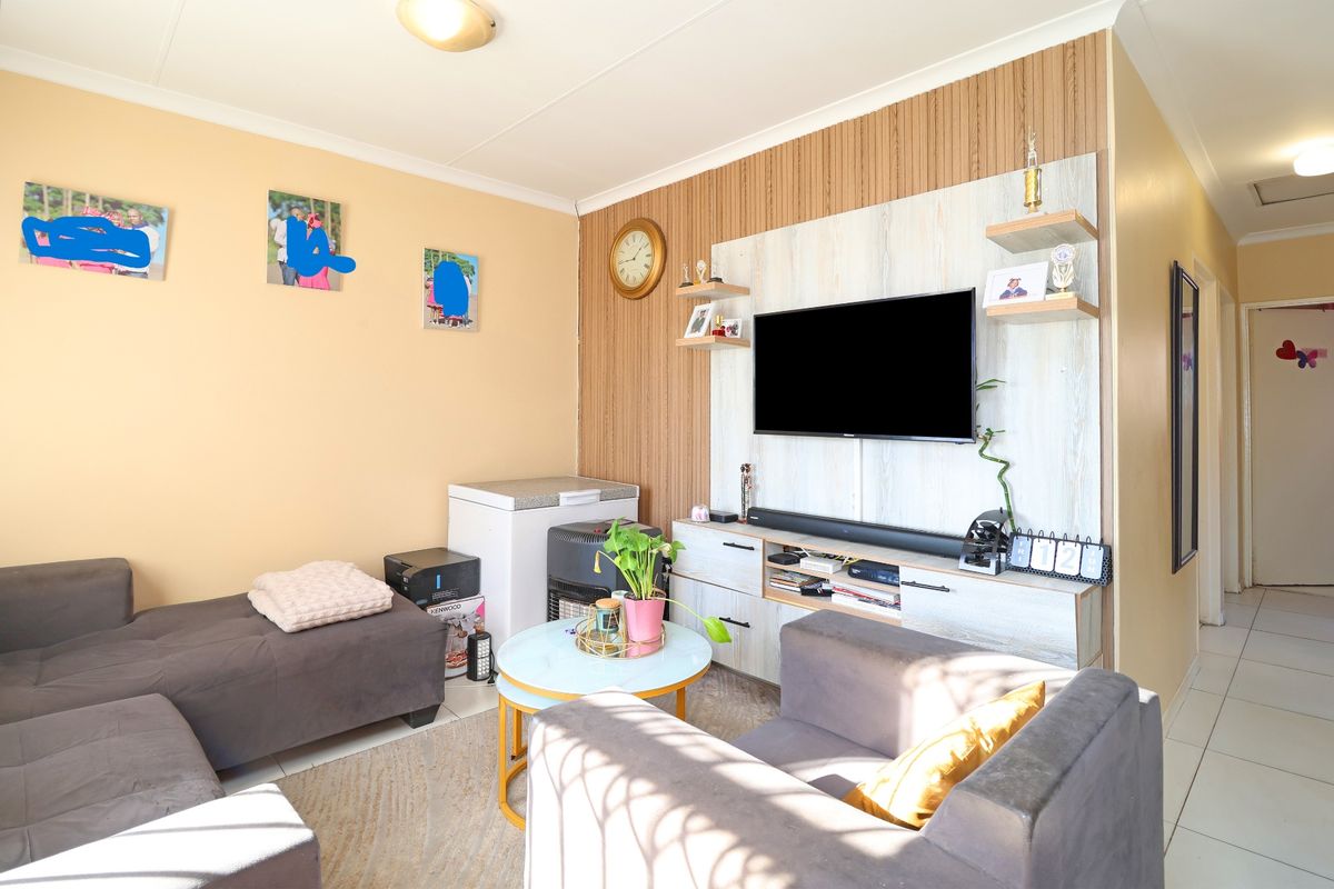 A living room featuring a built-in media unit with wood-look paneling, tiled flooring, and neutral wall finishes.