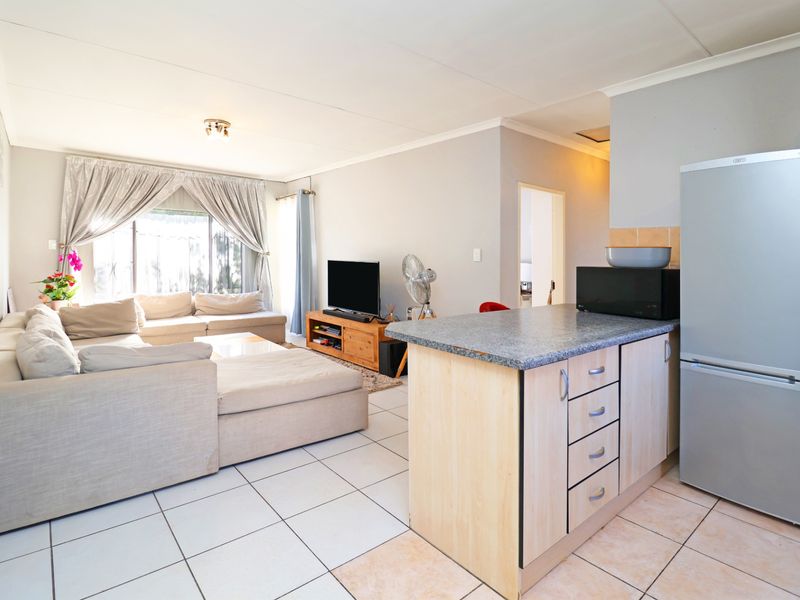 Open-plan living area featuring tiled flooring and a functional kitchen layout with built-in cabinetry and counter space.
