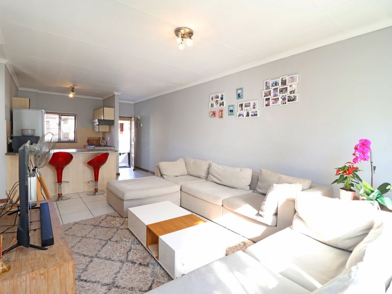 Open-plan living area featuring a kitchen with a breakfast bar, tiled flooring, and neutral wall finishes, creating a functional and connected living space.