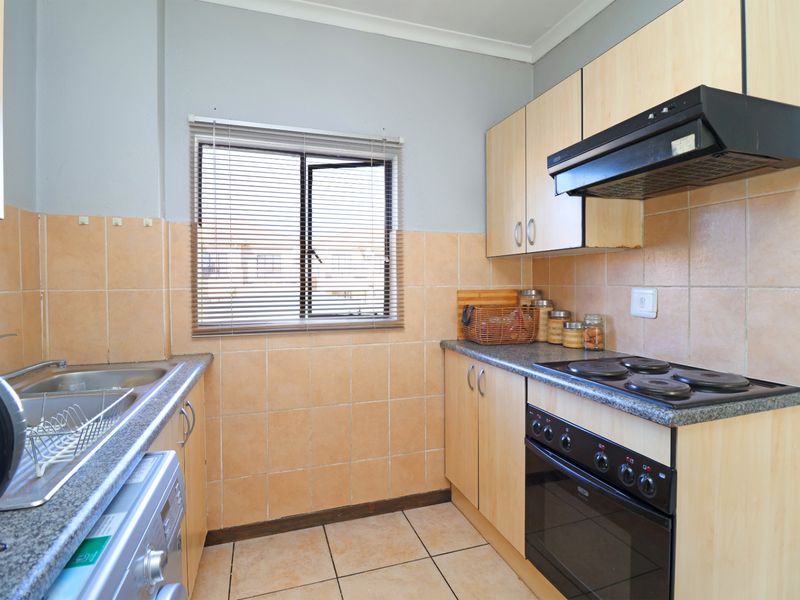 Functional kitchen featuring laminate cabinetry, granite countertops, built-in oven with extractor fan, and tiled finishes throughout.