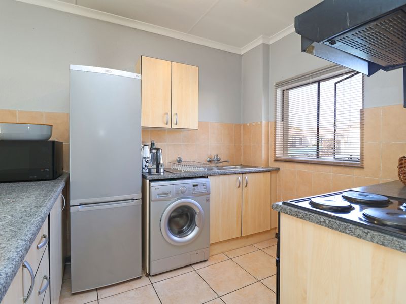 Functional kitchen featuring laminate cabinetry, granite-look countertops, ceramic tile backsplash, and integrated electric hob with extractor fan.
