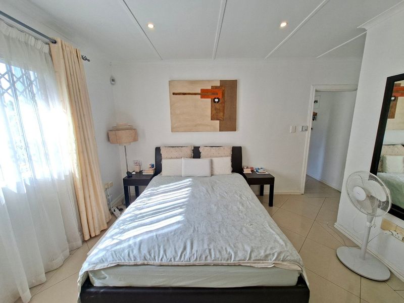 A well-lit bedroom featuring tiled flooring and recessed ceiling lights, providing a functional and comfortable sleeping space.