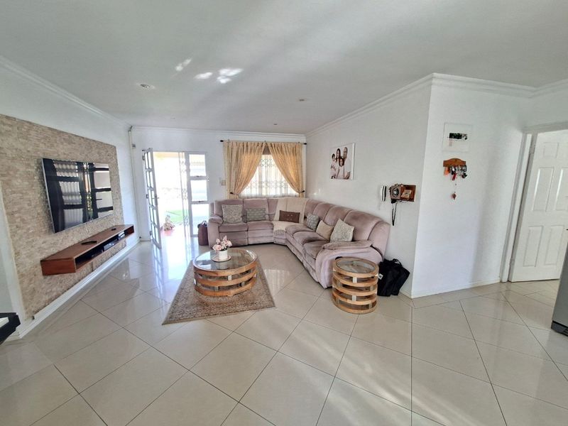 A bright and spacious living room featuring polished tiled flooring, a textured stone feature wall, and direct access to the outdoor area.