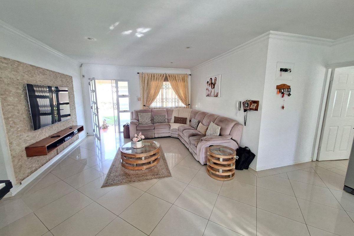 A bright and spacious living room featuring polished tiled flooring, a textured stone feature wall, and direct access to the outdoor area.
