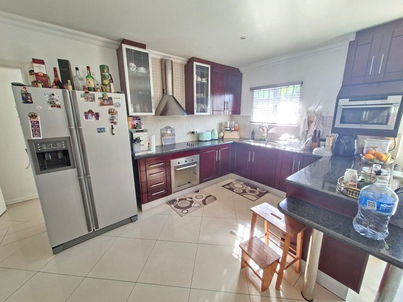 A functional kitchen featuring dark wood cabinetry, granite countertops, stainless steel appliances, and tiled flooring with a breakfast bar area.