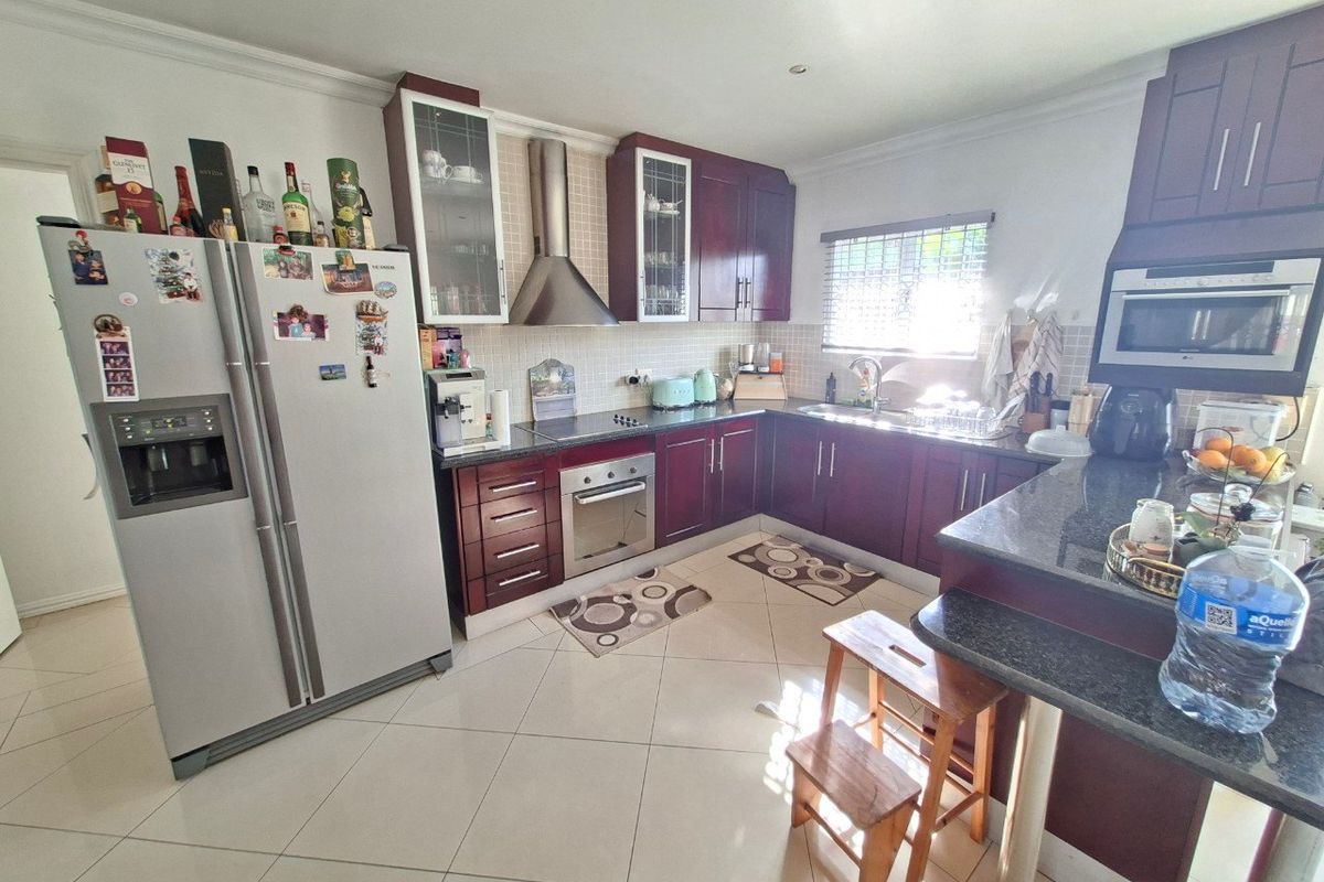 A functional kitchen featuring dark wood cabinetry, granite countertops, stainless steel appliances, and tiled flooring with a breakfast bar area.