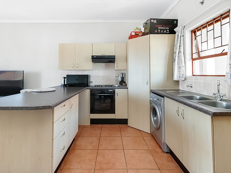 Functional kitchen featuring built-in cabinetry, gas hob, oven, extractor fan, and double bowl sink with tiled splashbacks and ceramic floor tiles.