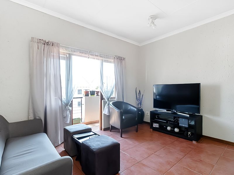 A living room featuring terracotta floor tiles and a sliding glass door providing access to a balcony.