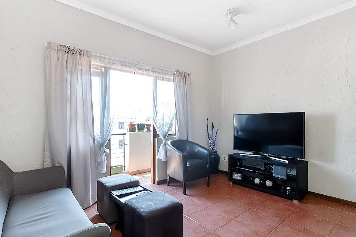 A living room featuring terracotta floor tiles and a sliding glass door providing access to a balcony.