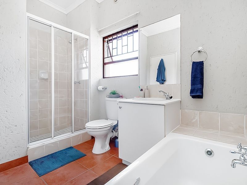 A functional bathroom featuring a shower enclosure, bathtub, vanity cabinet with basin, and tiled flooring, providing a practical layout for daily use.