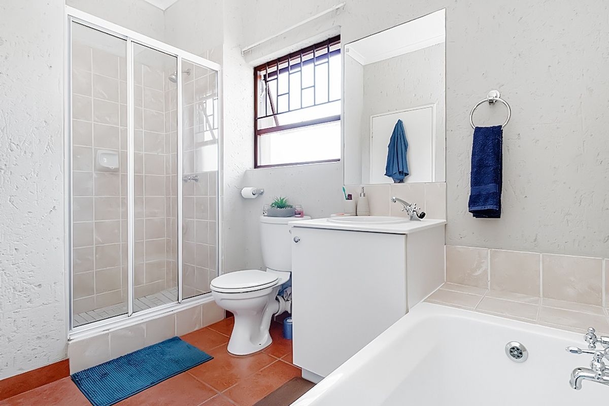 A functional bathroom featuring a shower enclosure, bathtub, vanity cabinet with basin, and tiled flooring, providing a practical layout for daily use.