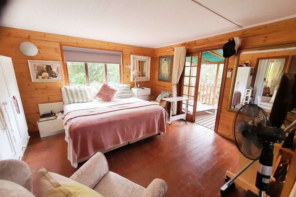 A bedroom featuring warm timber wall paneling and flooring, with direct access to an outdoor patio area through timber-framed sliding doors.
