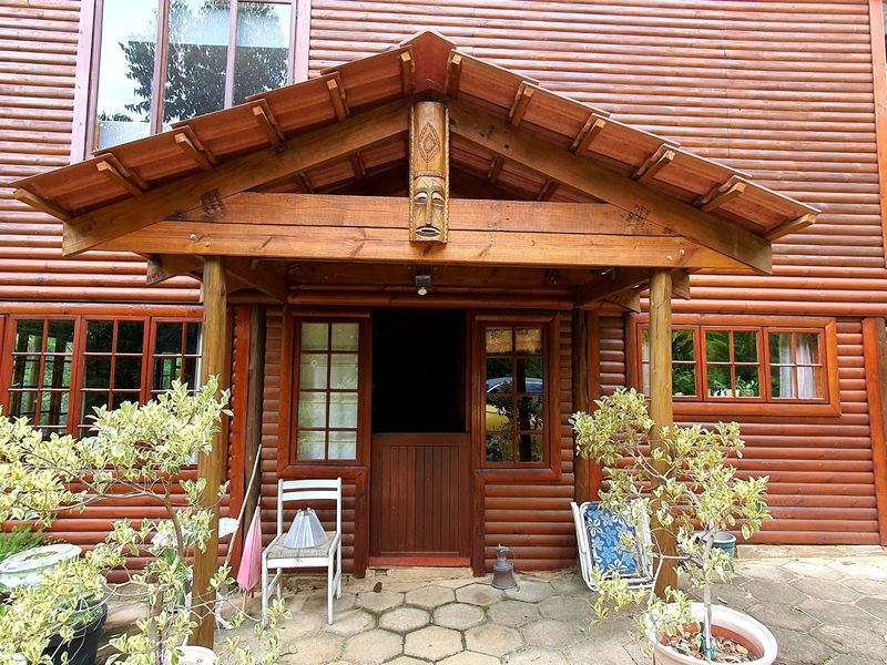 Front entrance of a timber log townhouse featuring a covered porch, stable-style door, and paved patio area.