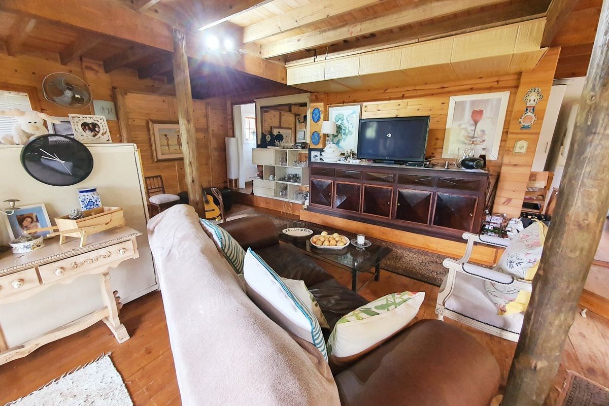 A rustic living room featuring exposed timber ceiling beams, timber wall cladding, and warm timber flooring, creating a cozy and traditional atmosphere.