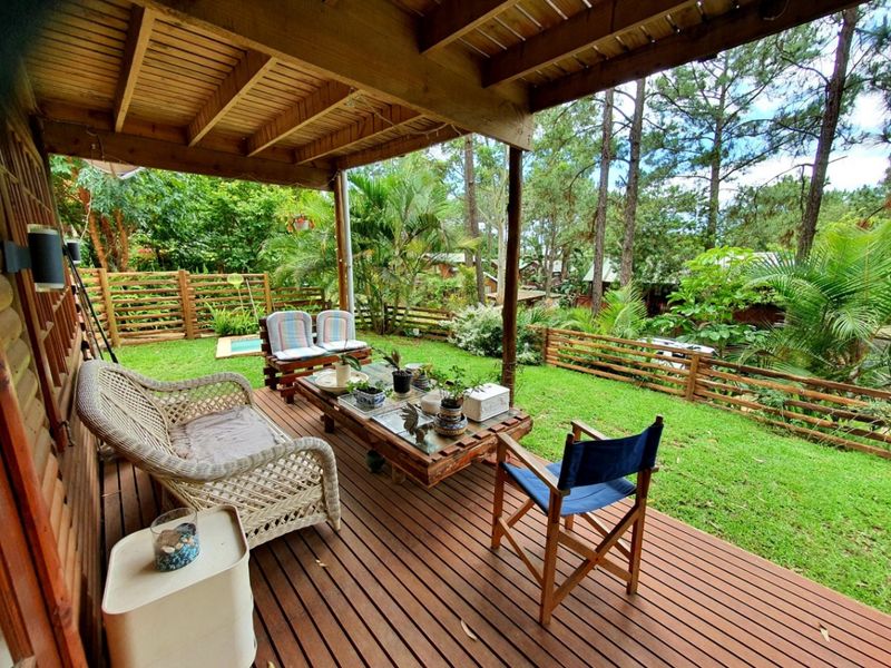 A covered timber deck patio overlooking a lush green garden with timber slat fencing and mature trees.