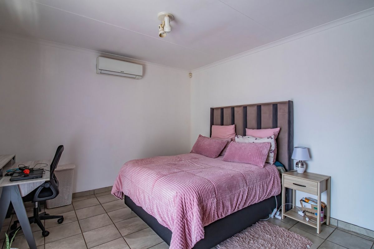 A bedroom featuring tiled flooring, a wall-mounted split-system air conditioner, and coved ceiling finishes.