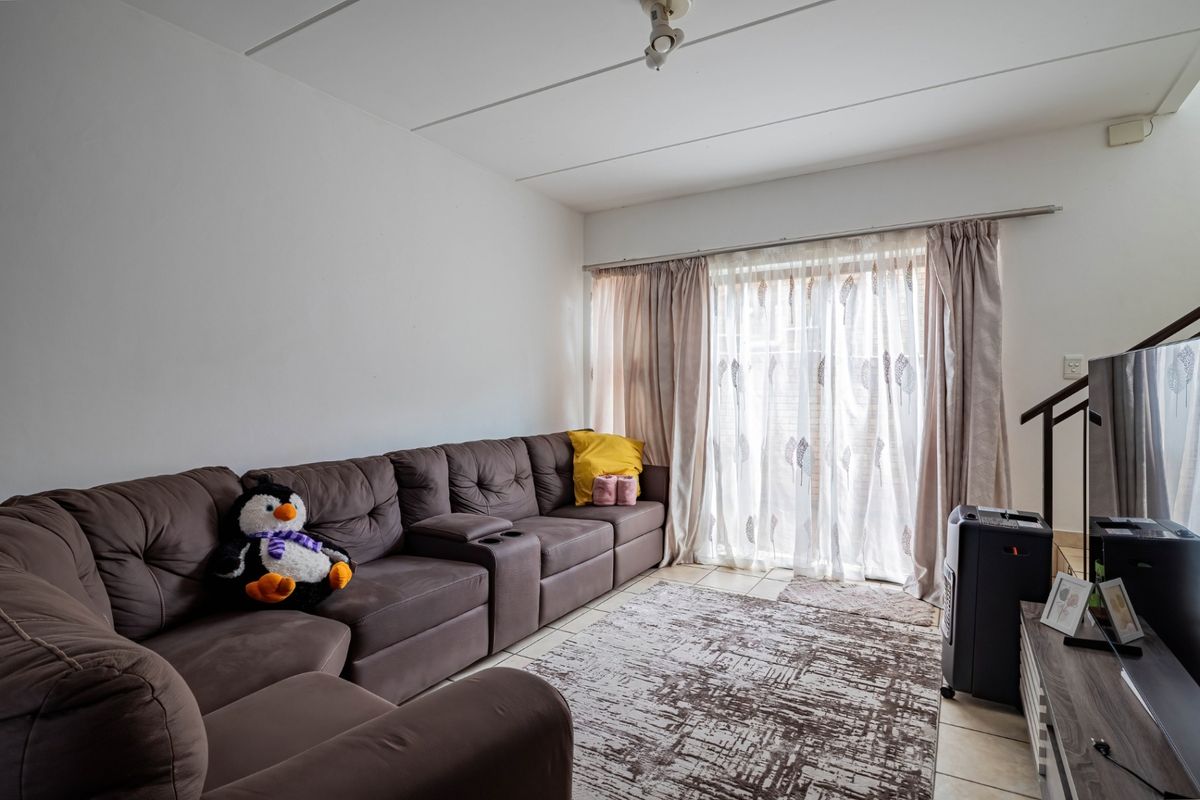 A comfortable living room featuring tiled flooring and a large sliding glass door that provides access to the outdoor area.
