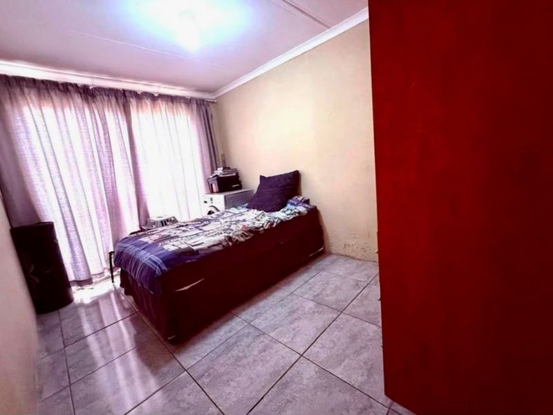 A bedroom featuring tiled flooring and cove cornicing, currently requiring cosmetic updates to the wall finishes.
