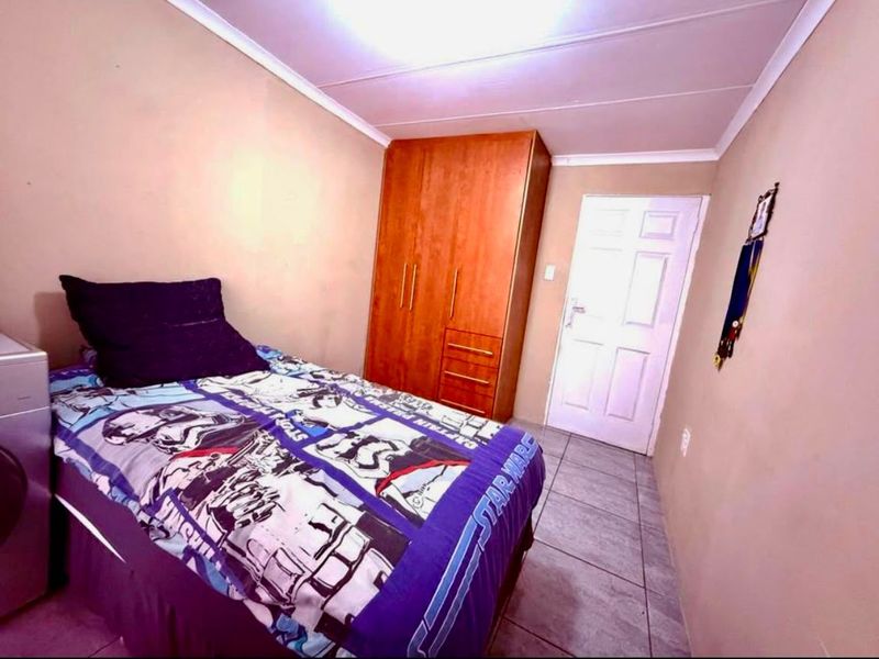 A functional bedroom featuring tiled flooring, a built-in wardrobe, and coved ceiling detailing.