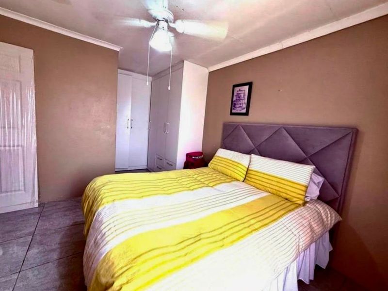 A bedroom featuring tiled flooring, built-in cupboards for storage, and a ceiling fan.