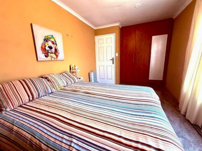 A bedroom featuring built-in wooden wardrobes, a panel door, and coved ceiling details.