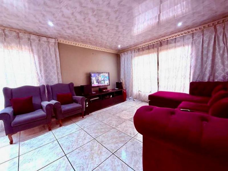 A living room featuring tiled flooring and a glossy ceiling finish with recessed lighting, providing a functional space for relaxation.