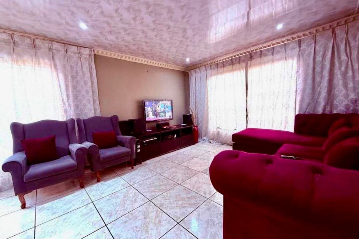 A living room featuring tiled flooring and a glossy ceiling finish with recessed lighting, providing a functional space for relaxation.
