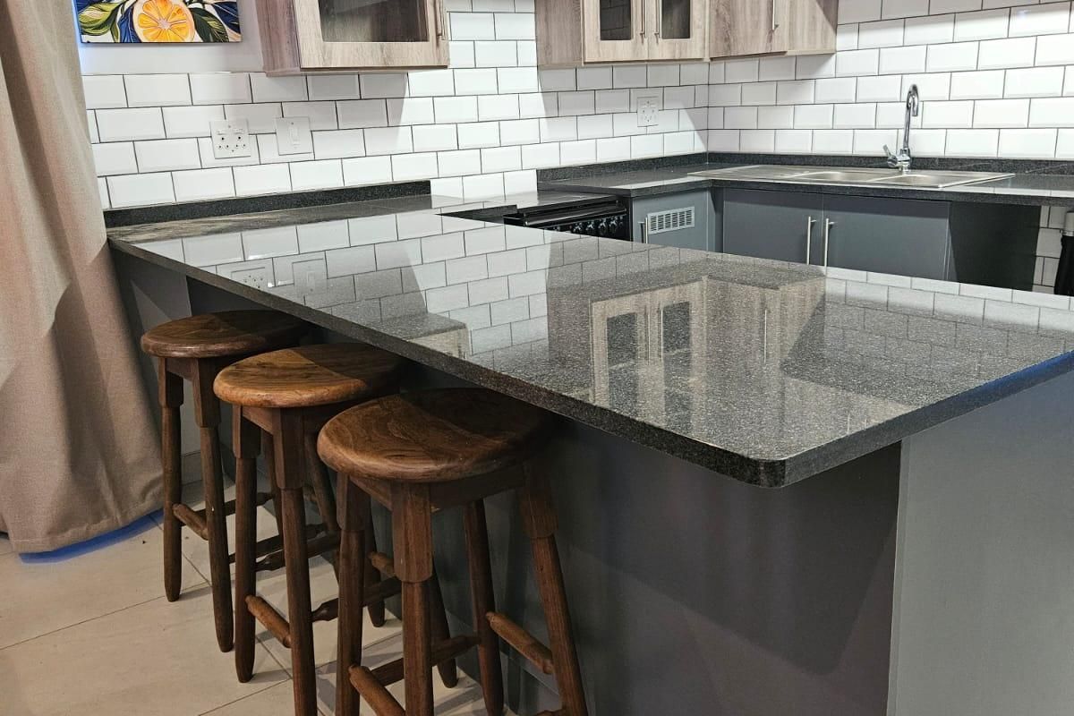 Modern kitchen featuring granite countertops, a breakfast bar, subway tile backsplash, and ample built-in cabinetry with a neutral color palette.