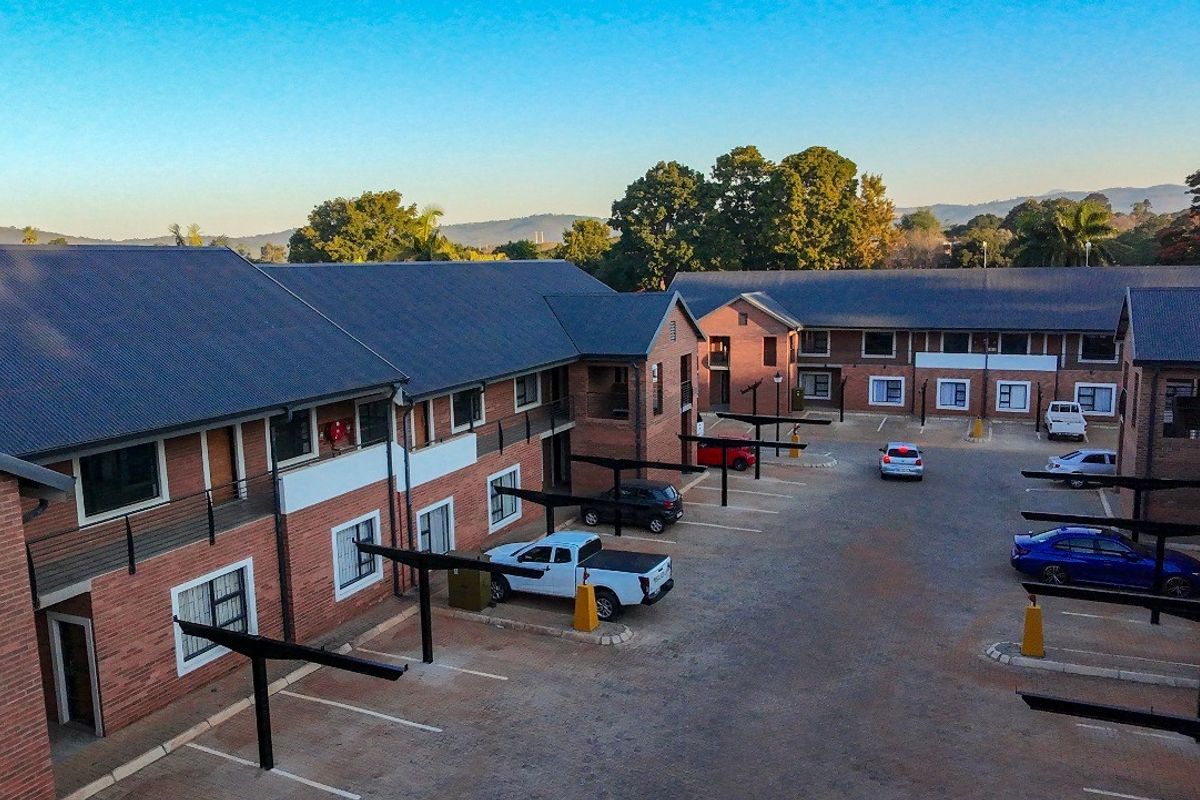 Aerial view of a multi-story apartment complex featuring brick facades, corrugated metal roofing, and dedicated covered parking bays.