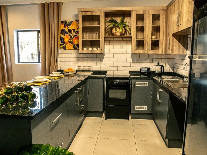 Modern kitchen featuring dark grey cabinetry, granite countertops, subway tile backsplash, and a freestanding oven, offering a functional and stylish cooking space.