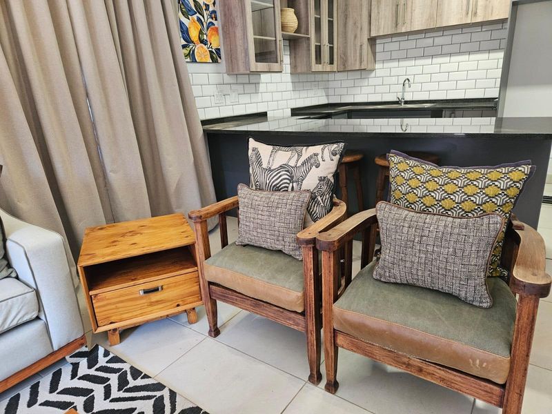 Open plan living area featuring a modern kitchen with granite countertops, subway tile backsplash, and neutral ceramic floor tiles.