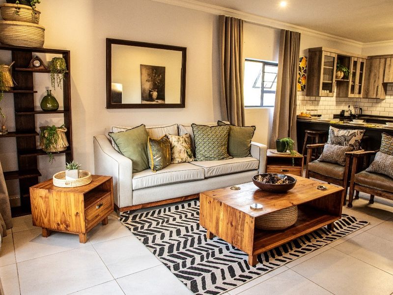 An open-plan living area featuring tiled floors, recessed lighting, and a functional kitchen with subway tile backsplash and wooden cabinetry.