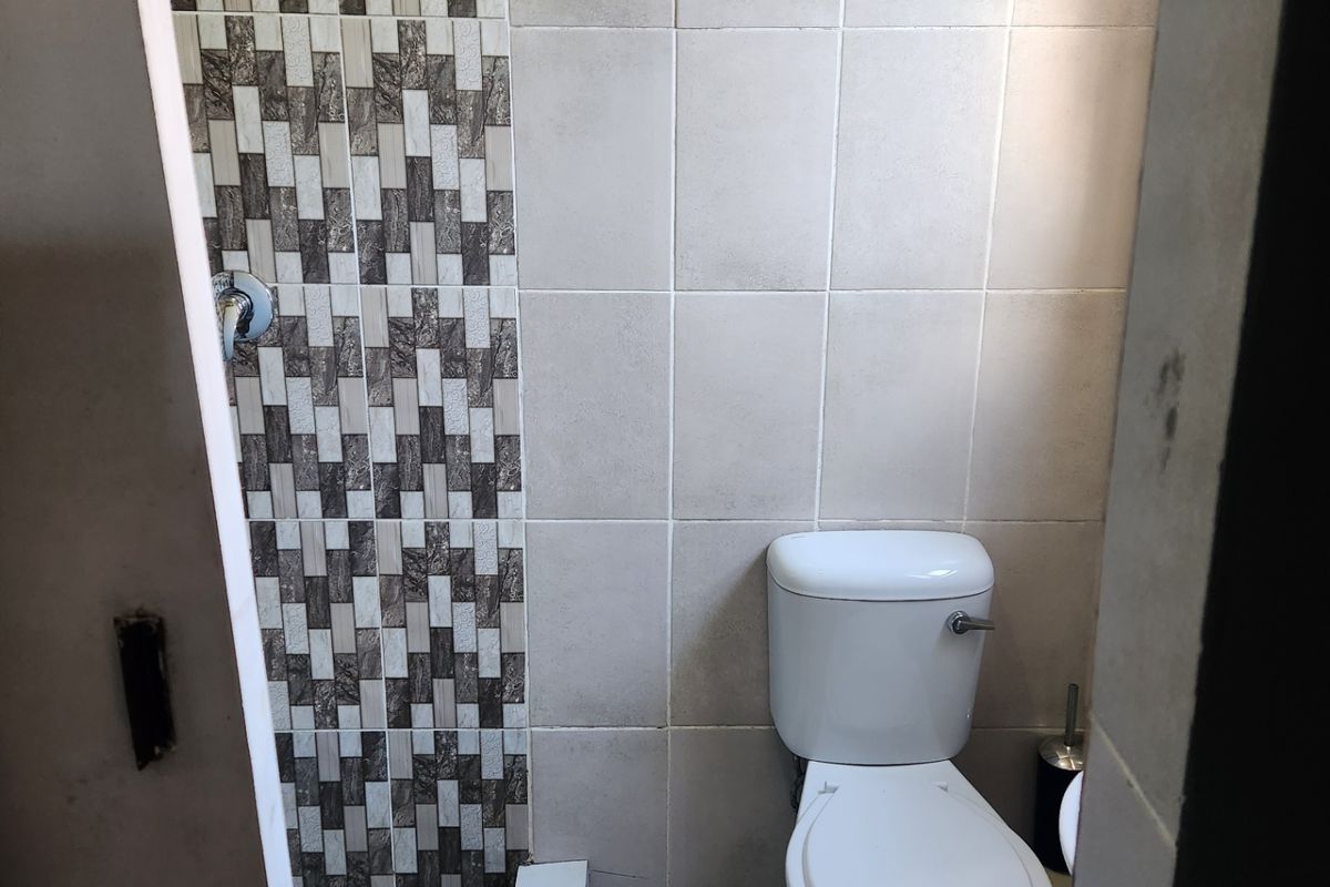 A compact bathroom featuring a standard toilet and a tiled shower area with decorative wall accents.
