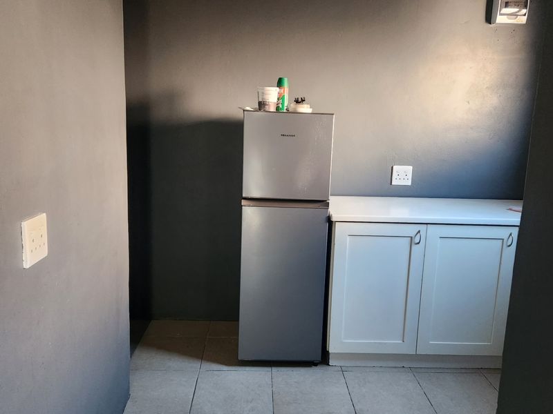 A compact kitchen area featuring tiled flooring, base cabinetry, and dark grey walls, requiring minor finishing touches to the electrical installations.
