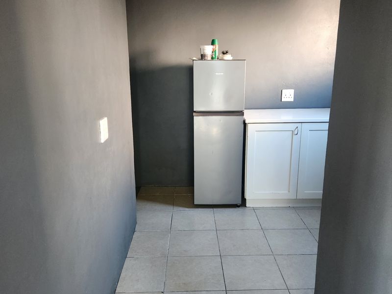 A compact kitchen area featuring tiled flooring, base cabinetry with a countertop, and dark grey wall finishes.