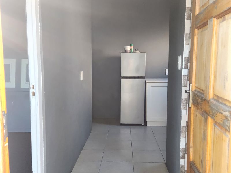 A view through a doorway into a small kitchen area featuring tiled flooring and basic built-in cabinetry.