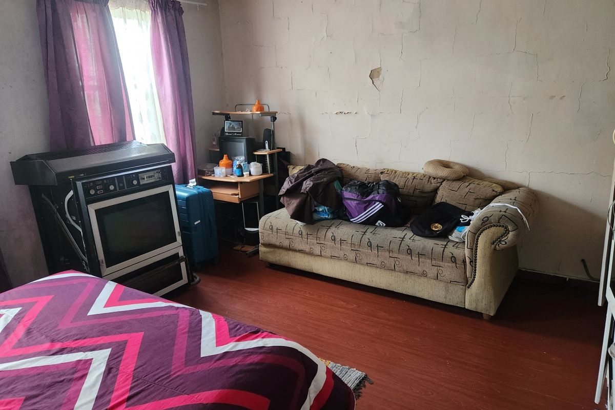 A bedroom featuring laminate flooring and walls requiring significant repair and repainting to restore the space.